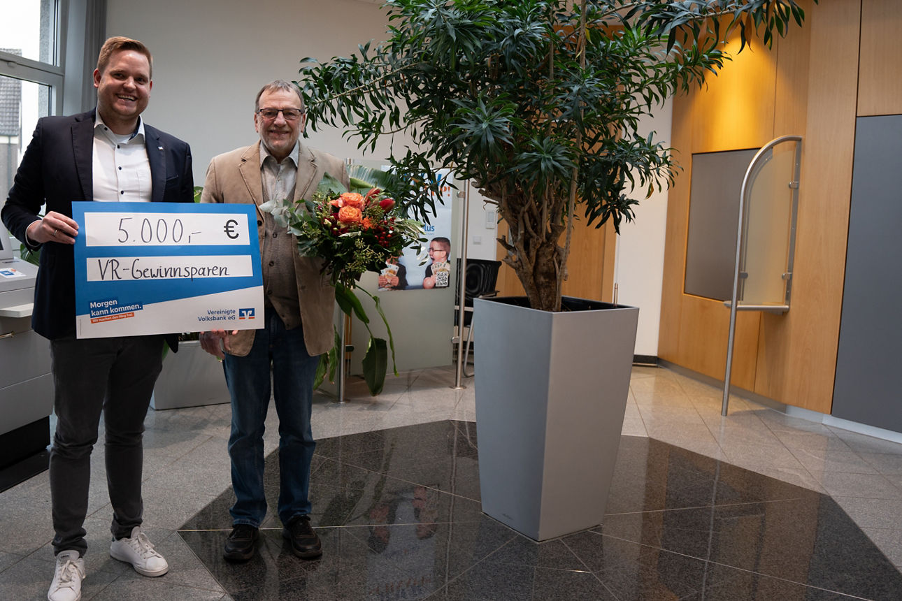 Zwei Männer mit einem Scheck über 5000€