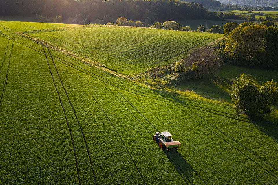 Ein Traktor fährt über ein grünes Feld.