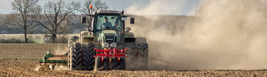 Ein Traktor pflügt ein staubiges Feld