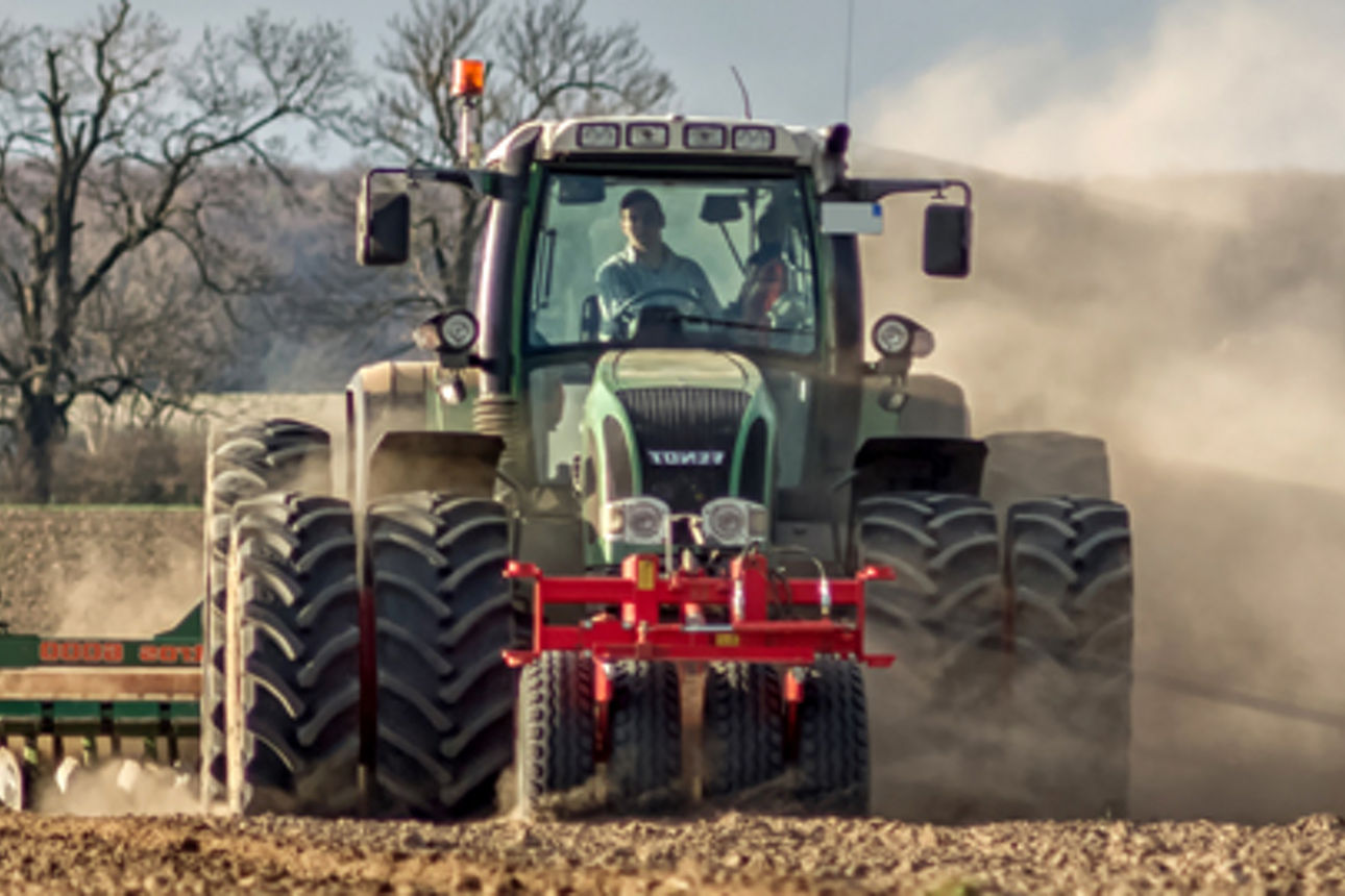 Ein Traktor pflügt ein staubiges Feld