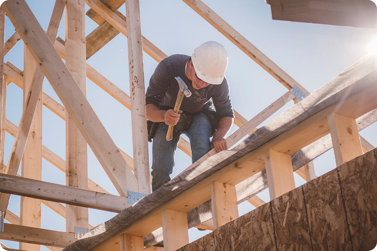Ein Handwerker hämmert eine Holzlatte in ein Dach