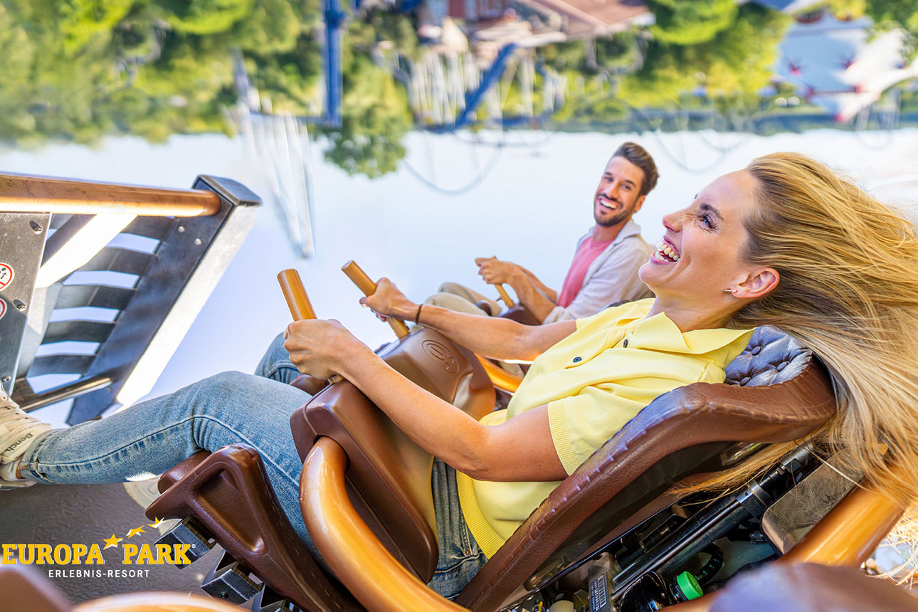 2 junge Leute sitzen in einer Achterbahn