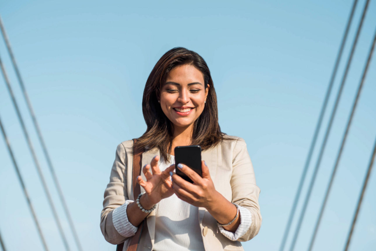 Junge Frau schaut auf ihr Handy und freut sich