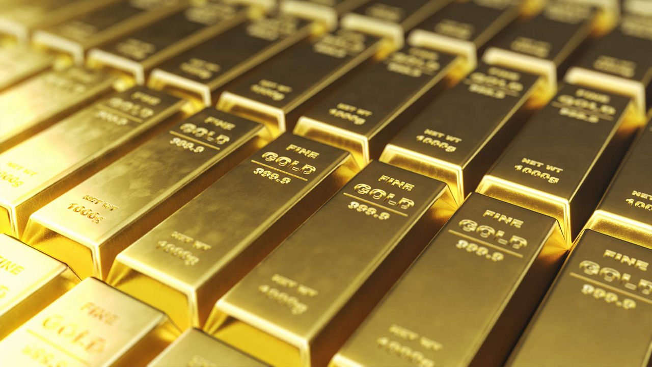 Mehrere glänzende Goldbarren liegen ordentlich nebeneinander gestapelt. Jeder Barren ist mit der Aufschrift "FINE GOLD 999.9" und dem Gewicht 1000 Gramm geprägt. 