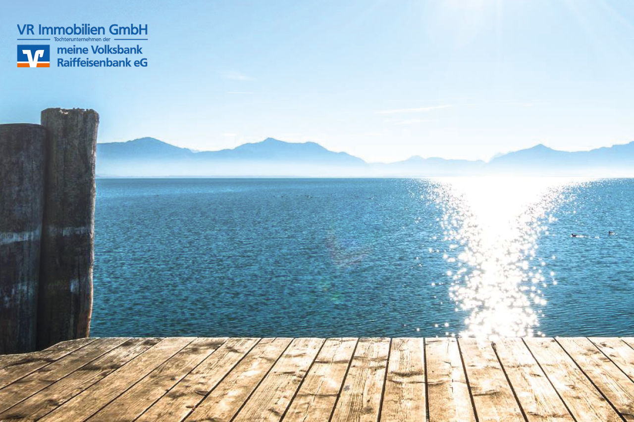 Ausblick auf einen See bei Sonnenschein und blauem Himmel vom Steg aus
