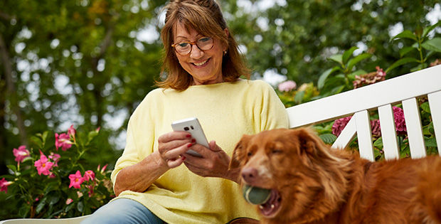 Unsere Kontomodelle Frau mtit Smartphone auf einer Bank im Grünen