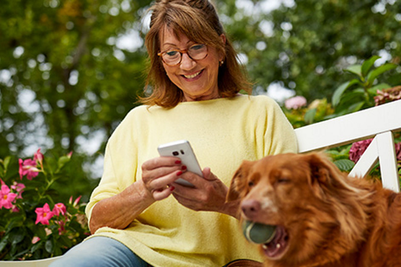 Unsere Kontomodelle Frau mtit Smartphone auf einer Bank im Grünen