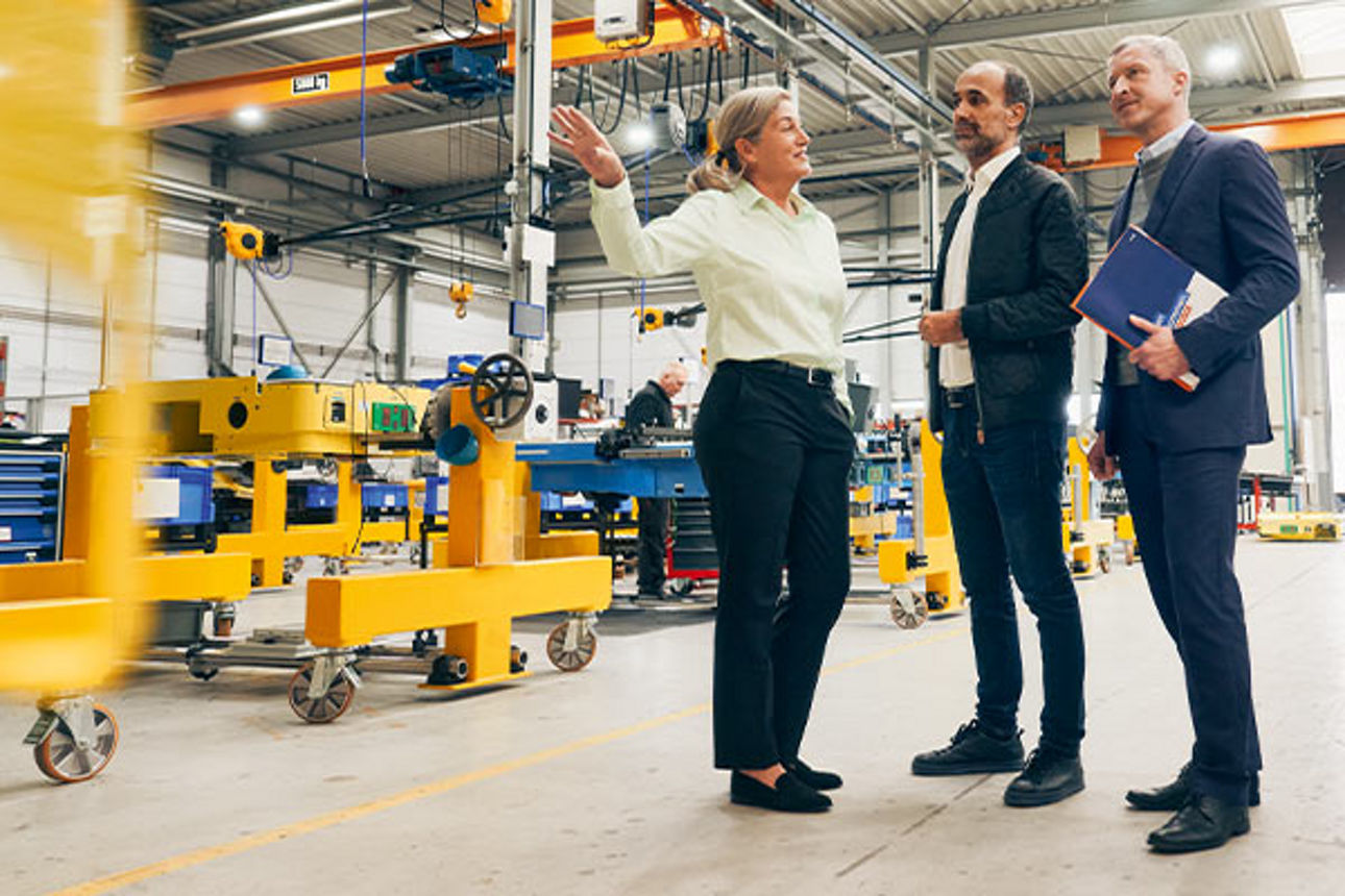 Drei Geschäftsleute stehen in einer Werkhalle