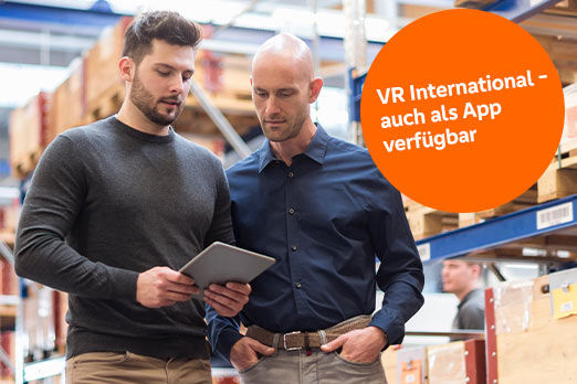Zwei Männer bei der Arbeit in einer Lagerhalle schauen gemeinsam auf ein Tablet