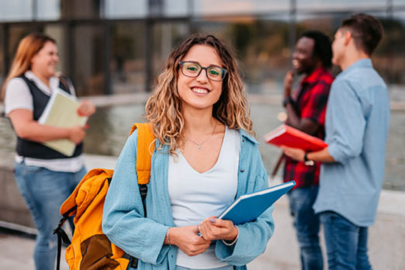 schuelerin-steht-vor-schule-mit-heft-in-der-hand