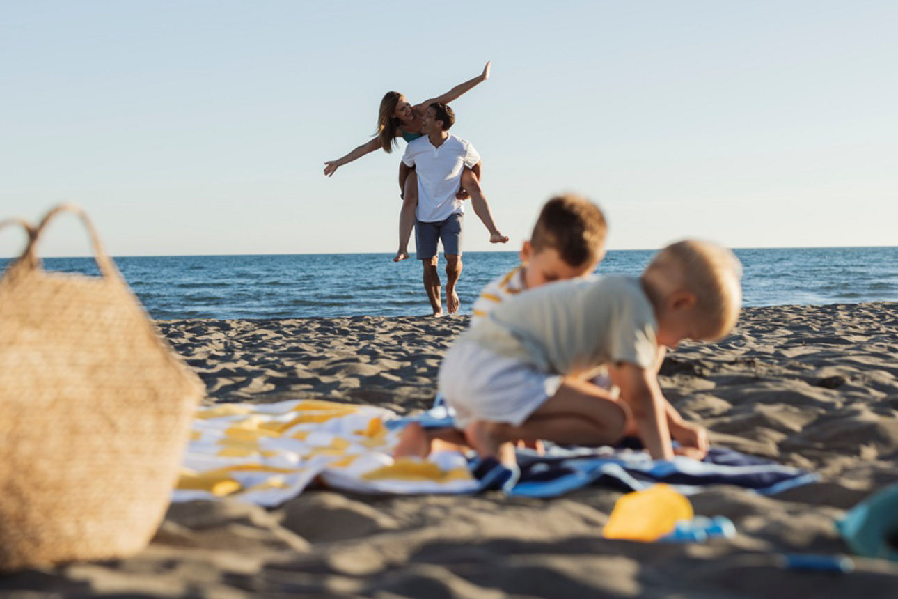 Glückliche Familie, die im Sommerurlaub Spaß am Strand hat