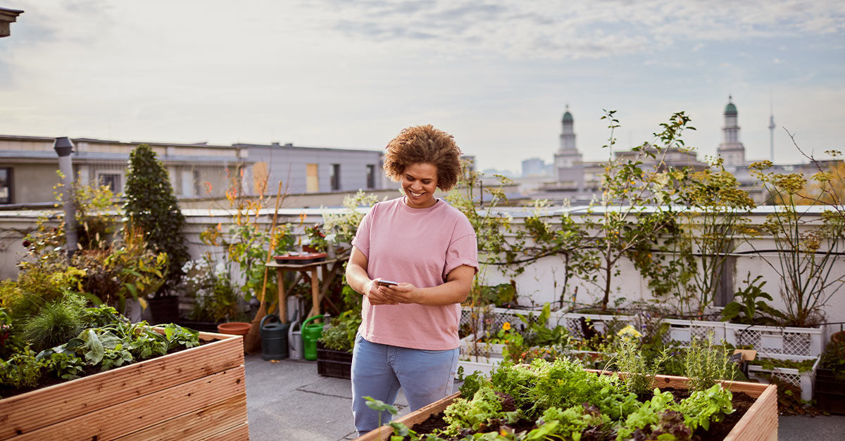 Frau mit Smartphone auf Dachterrasse