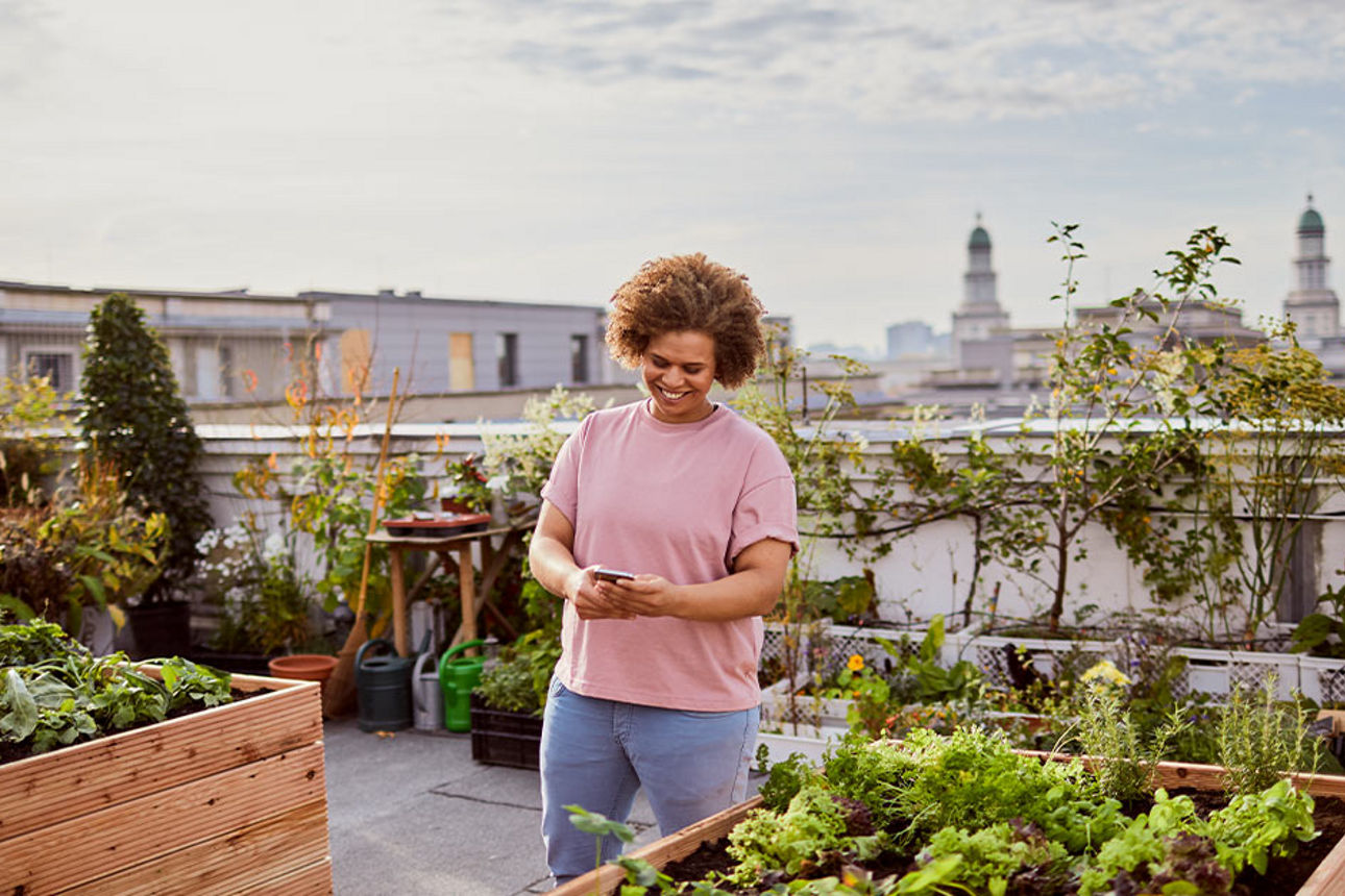 Frau mit Smartphone auf Dachterrasse
