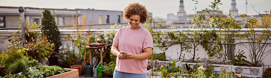 Frau mit Smartphone auf Dachterrasse