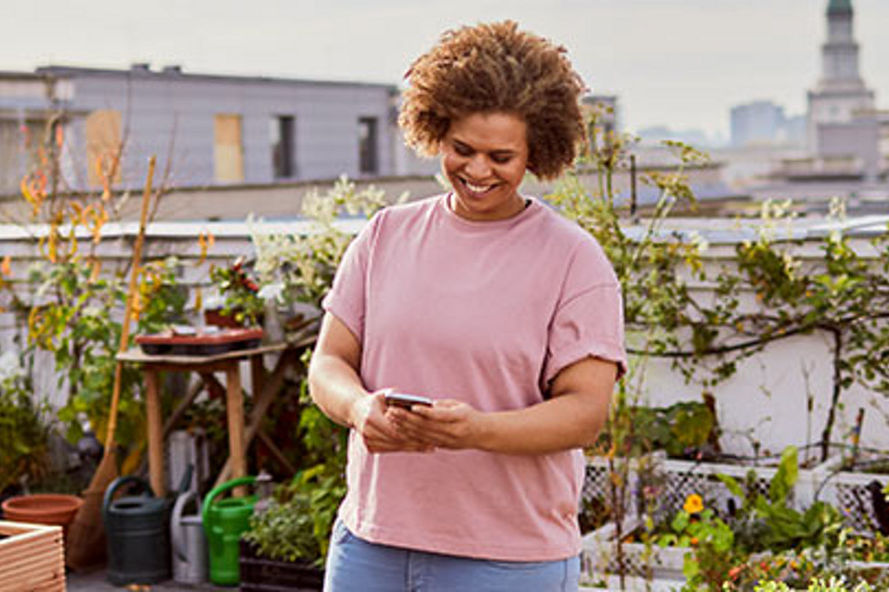 Frau mit Smartphone auf Dachterrasse