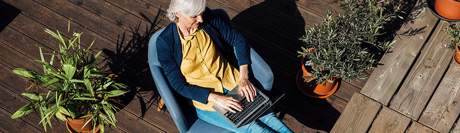 Eine Frau, die auf einem Stuhl sitzt und an ihrem Laptop arbeitet