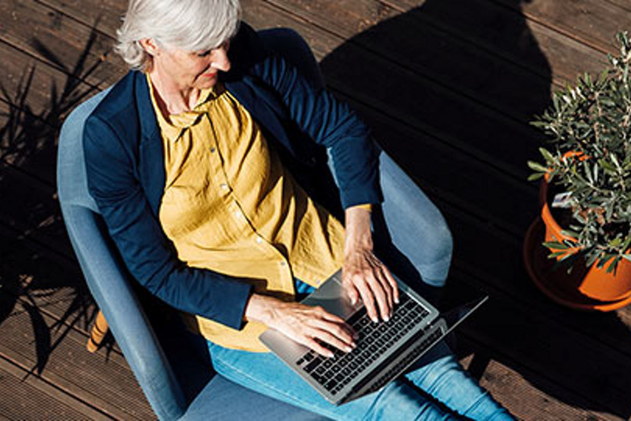 Eine Frau, die auf einem Stuhl sitzt und an ihrem Laptop arbeitet