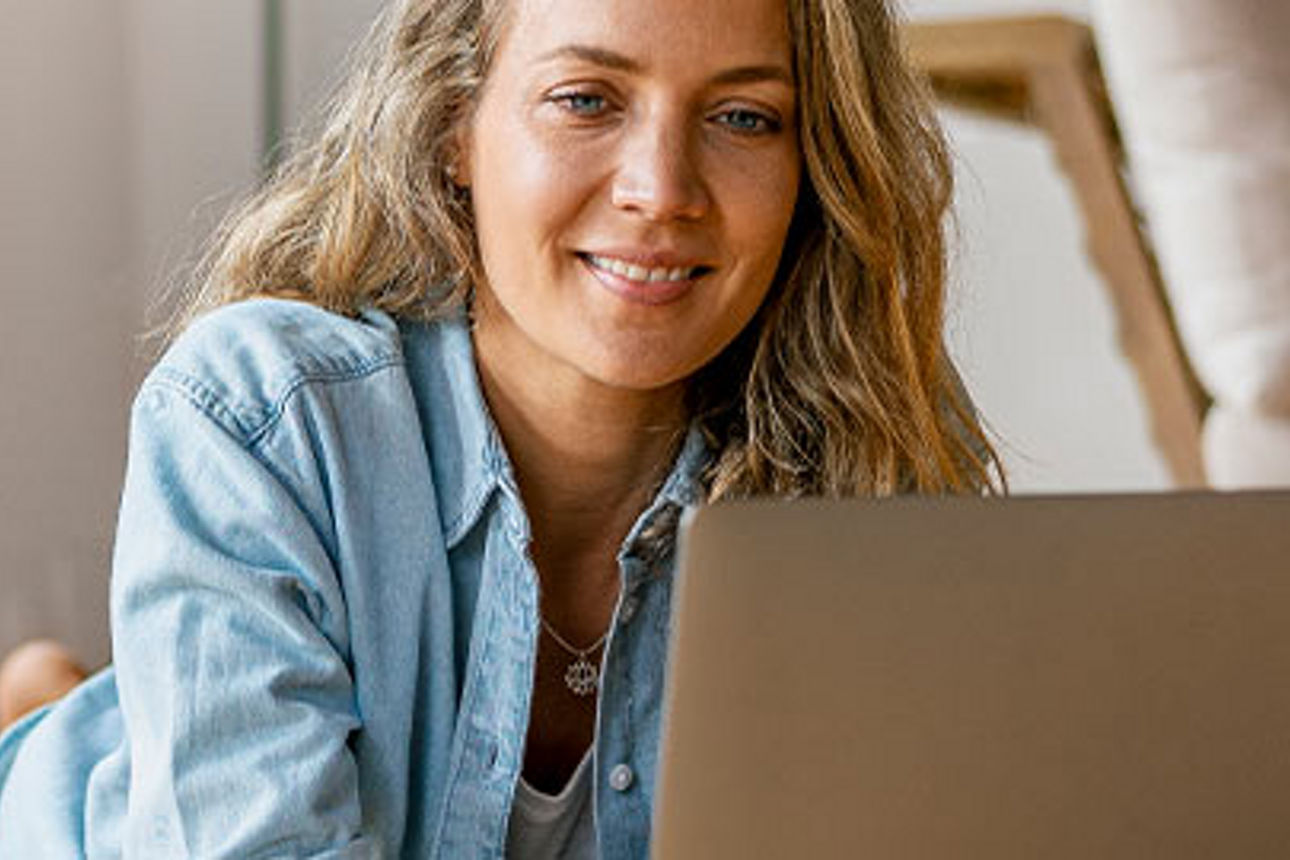 Frau liegt auf dem Boden und schaut in ihren Laptop