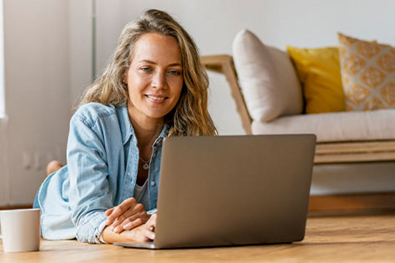 Frau sitzt auf dem Boden vor einem Laptop