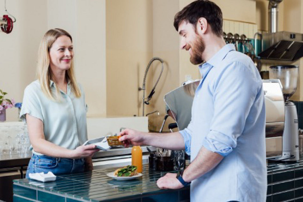 Junger Mann zahlt beim Bäcker kontaktlos