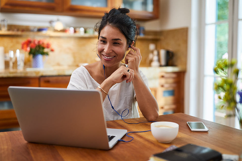Eine junge Frau telefoniert und arbeitet am Laptop