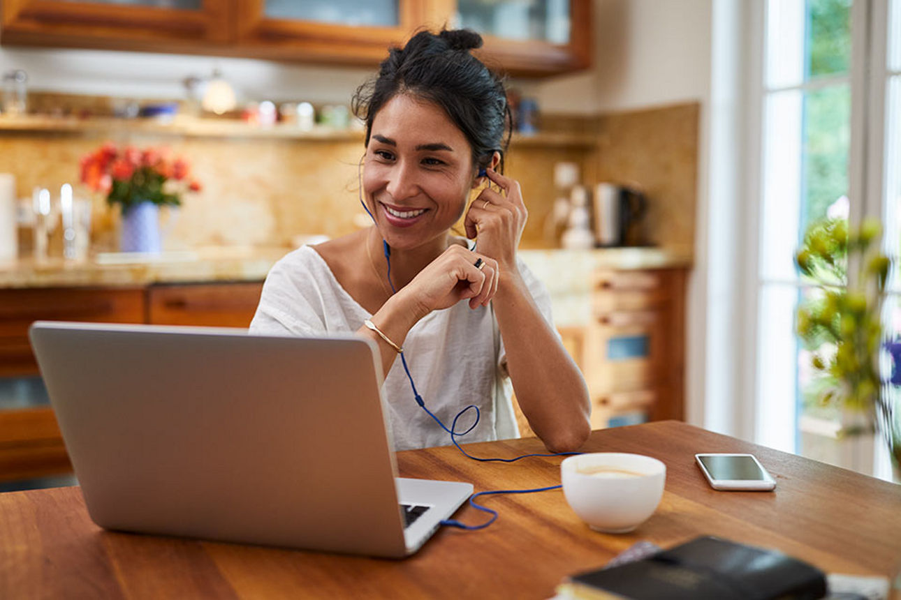 Eine junge Frau telefoniert und arbeitet am Laptop
