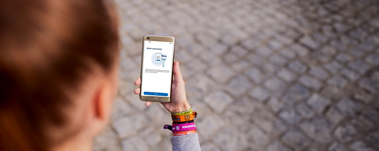 Frau mit einem Smartphone in der Hand, auf der die VR SecureGo plus App geöffnet ist