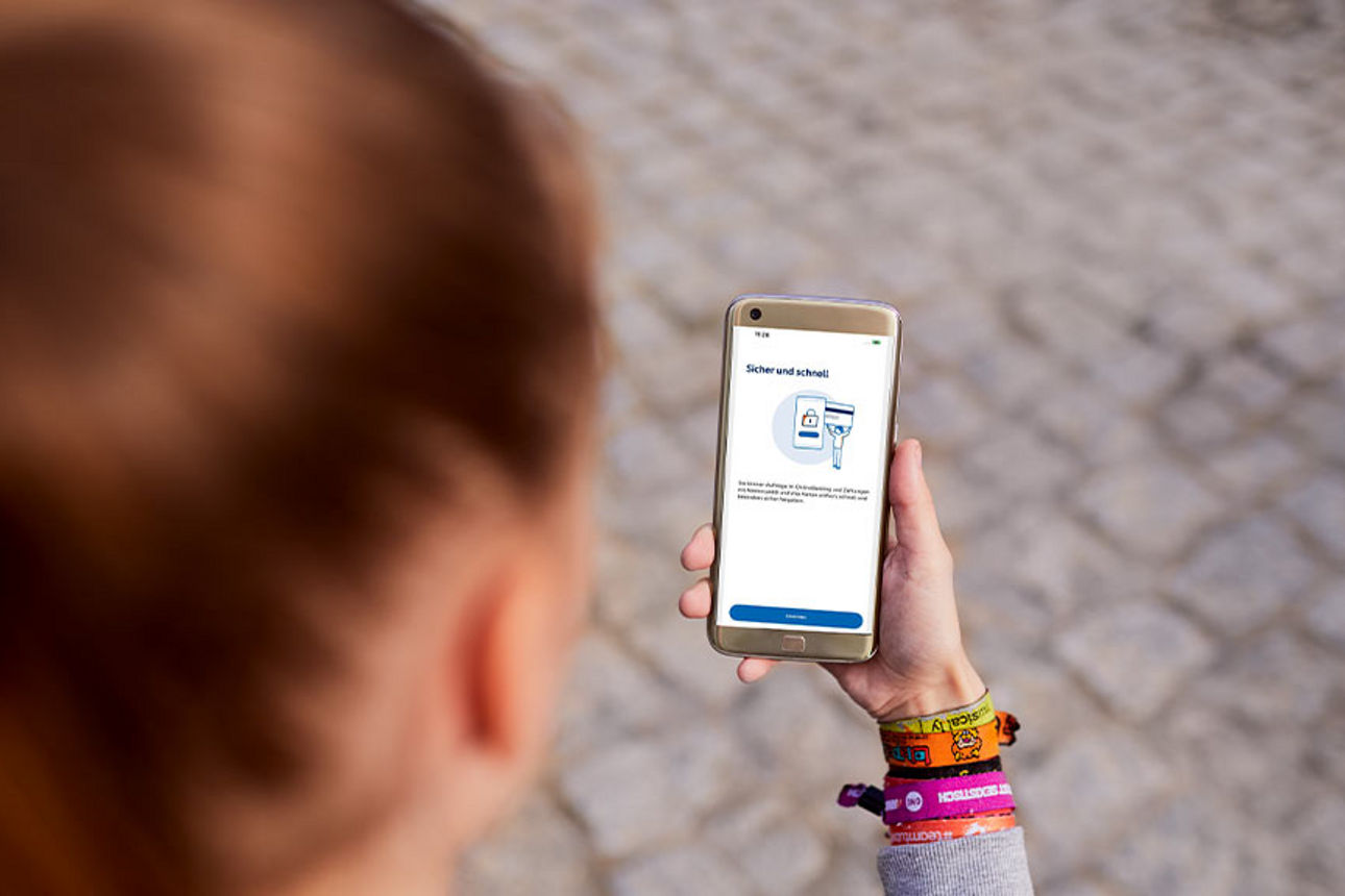 Frau mit einem Smartphone in der Hand, auf dem die VR SecureGo App geöffnet ist