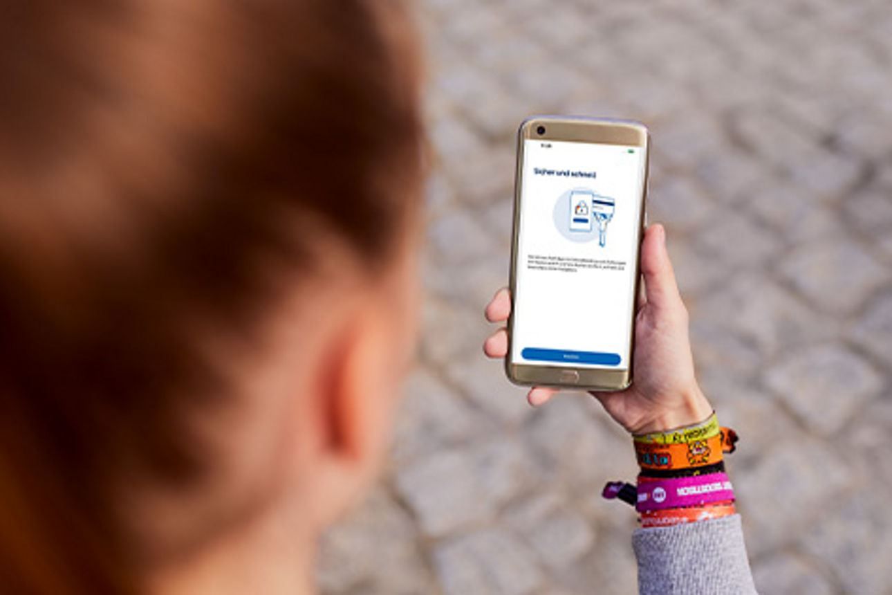 Frau mit einem Smartphone in der Hand, auf der die VR SecureGo plus App geöffnet ist