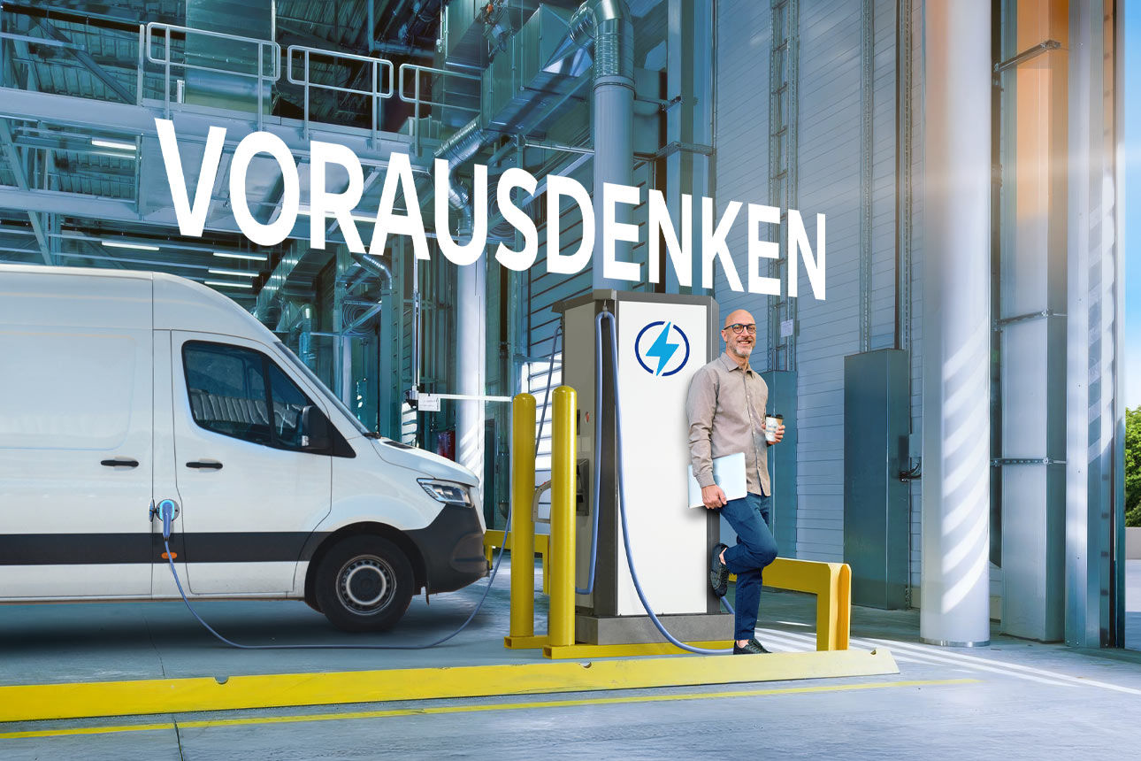 Ein Mann steht in einer Halle und lehnt an einer E-Ladesäule. Darüber steht das Wort 'VORAUSDENKEN'