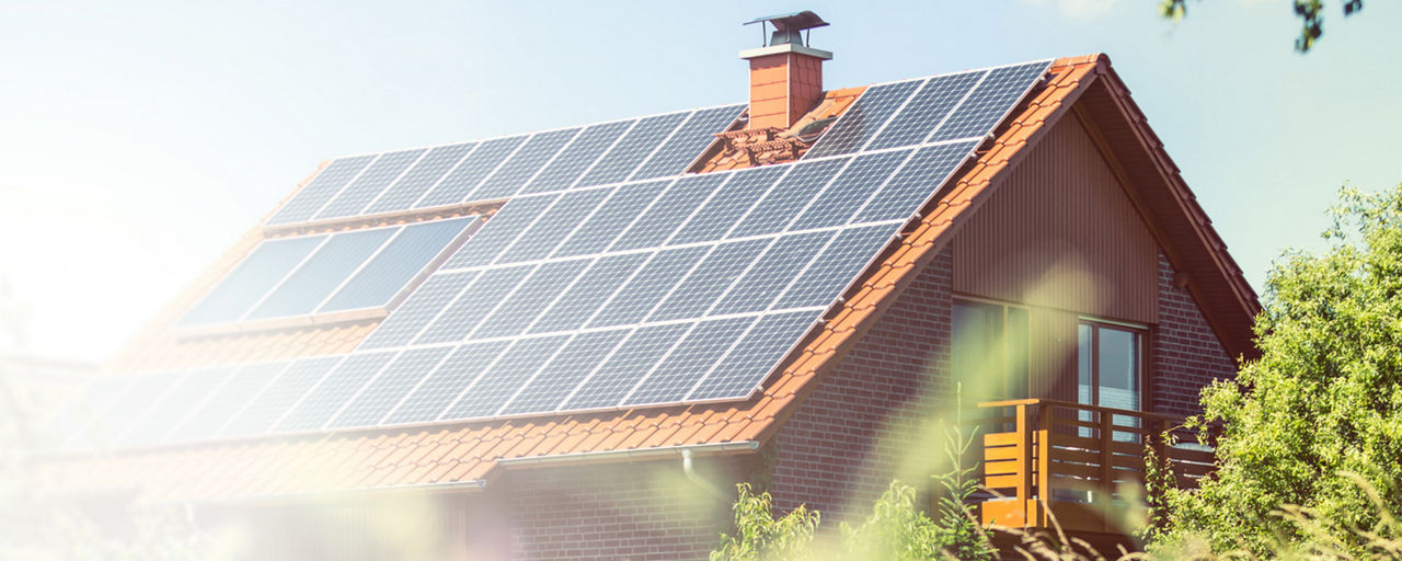 Ein Haus im Grünen mit Solaranlage auf dem Dach im Sonnenschein.