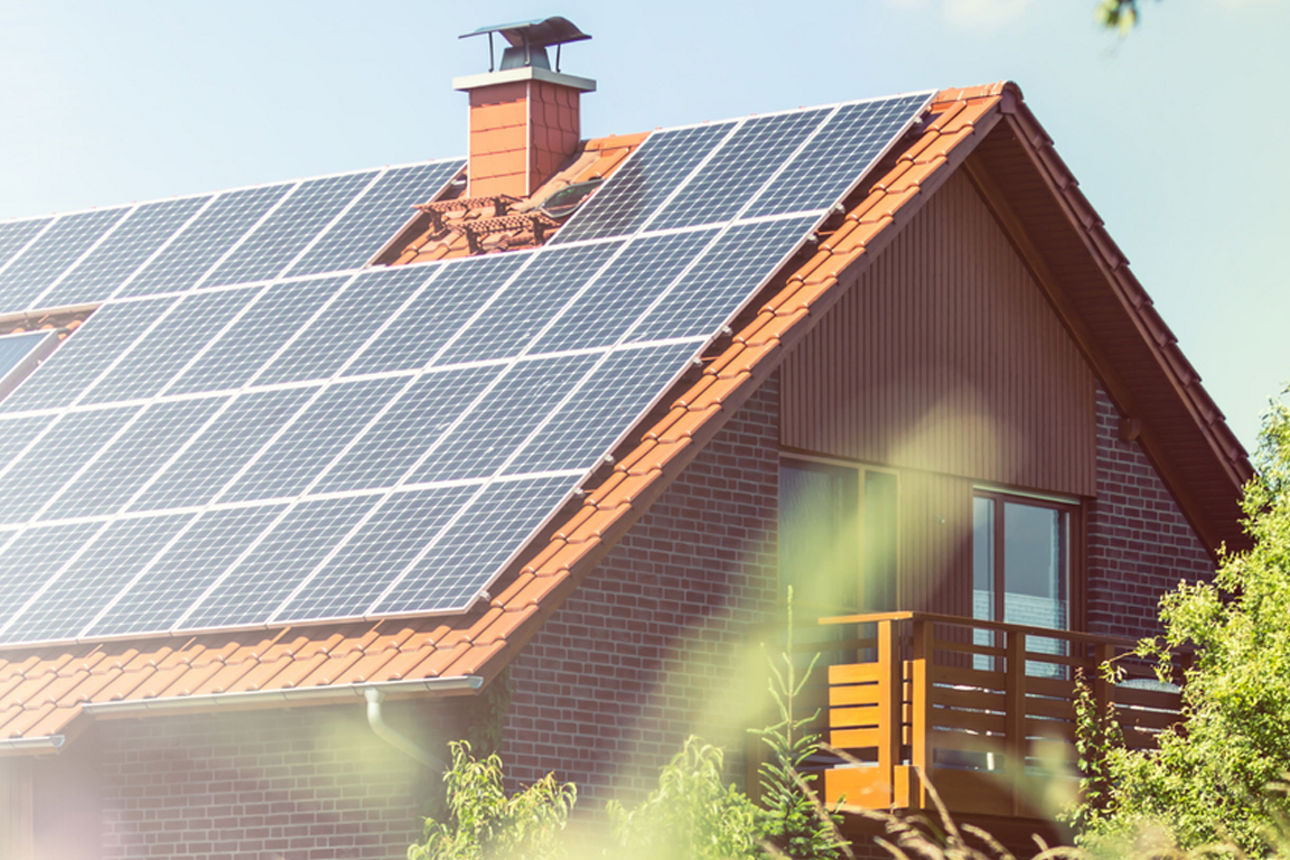 Ein Haus im Grünen mit Solaranlage auf dem Dach im Sonnenschein.