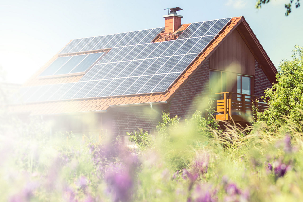 Ein Haus im Grünen mit Solaranlage auf dem Dach im Sonnenschein.