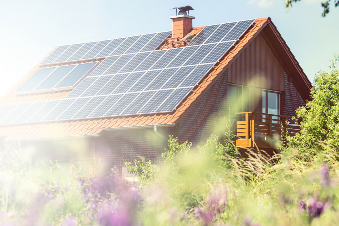 Ein Haus im Grünen mit Solaranlage auf dem Dach im Sonnenschein.