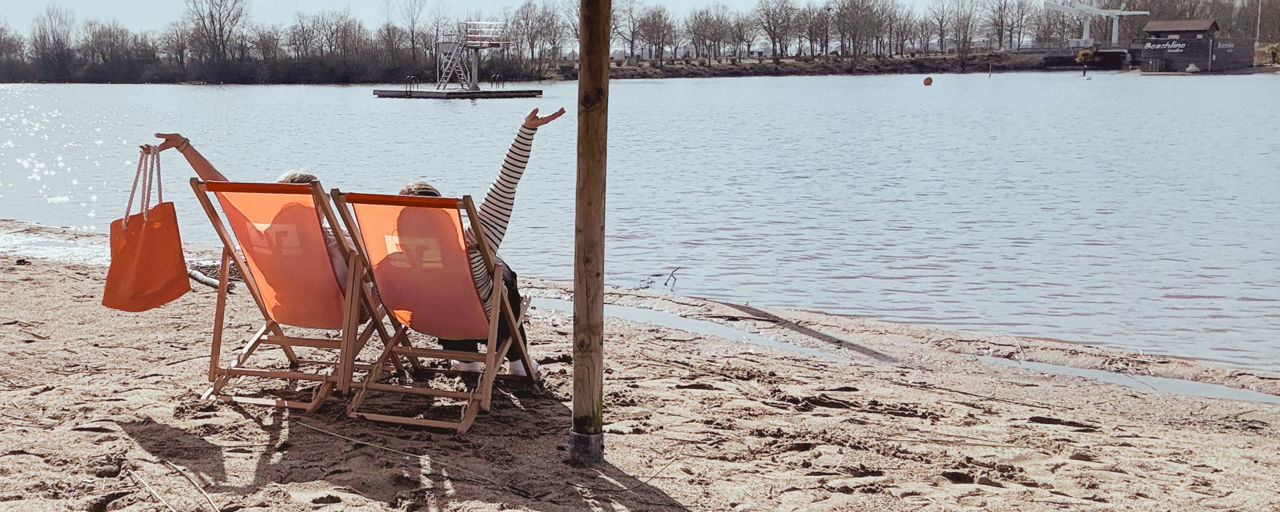 Zwei Frauen sitzen in einem Volksbank Sonnenstuhl am Strand
