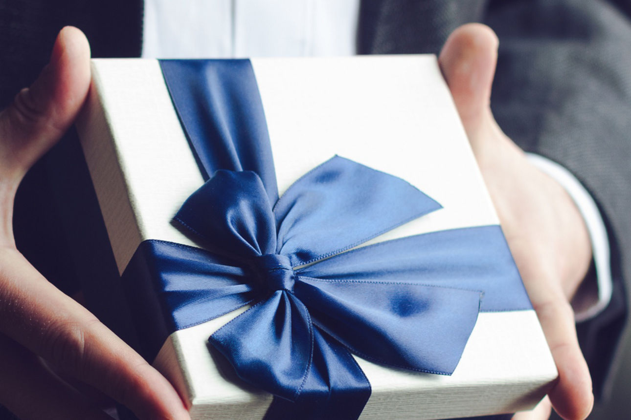 Großaufnahme von Mann im Anzug, der ein Geschenk überreicht