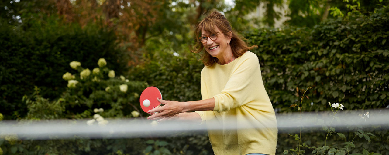 Eine Frau spielt Tischtennis im Garten