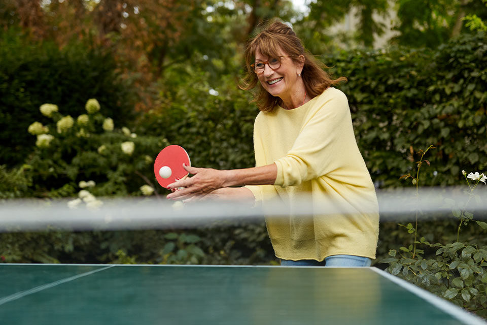 Eine Frau spielt Tischtennis im Garten