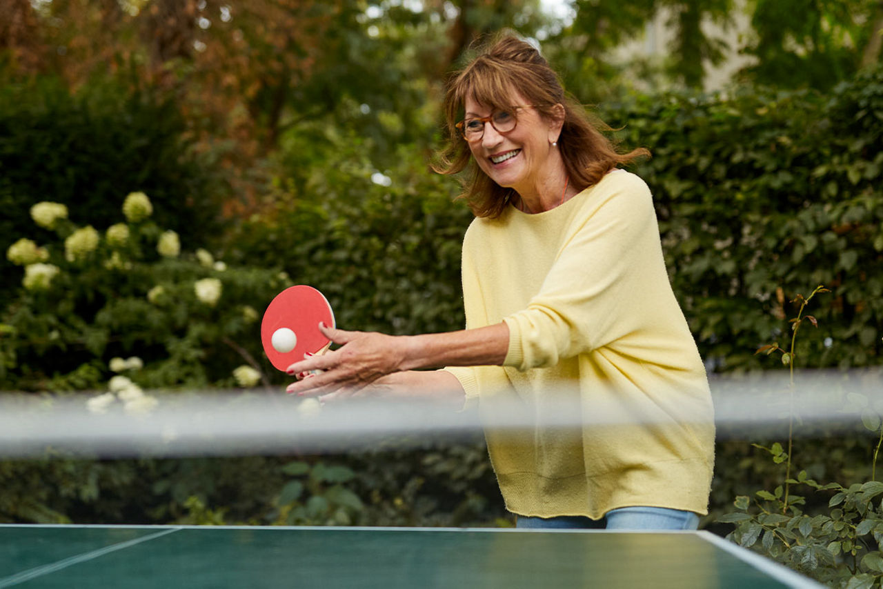 Eine Frau spielt Tischtennis im Garten