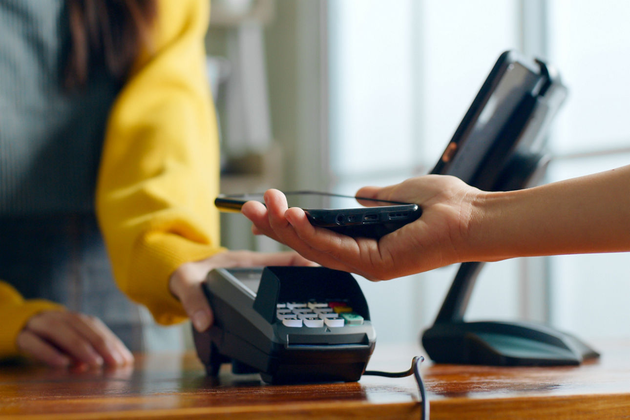 Ein Kunde bezahlt mit dem Handy im Café-Restaurant. Konzept für bargeldlose Zahlungen und Geldtransfers.