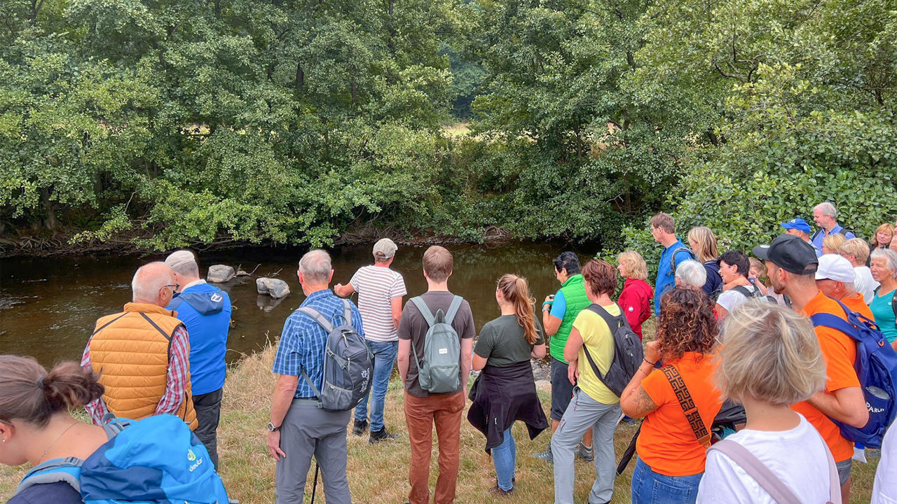 Eine Gruppe von Menschen steht am Flussufer der Wied.