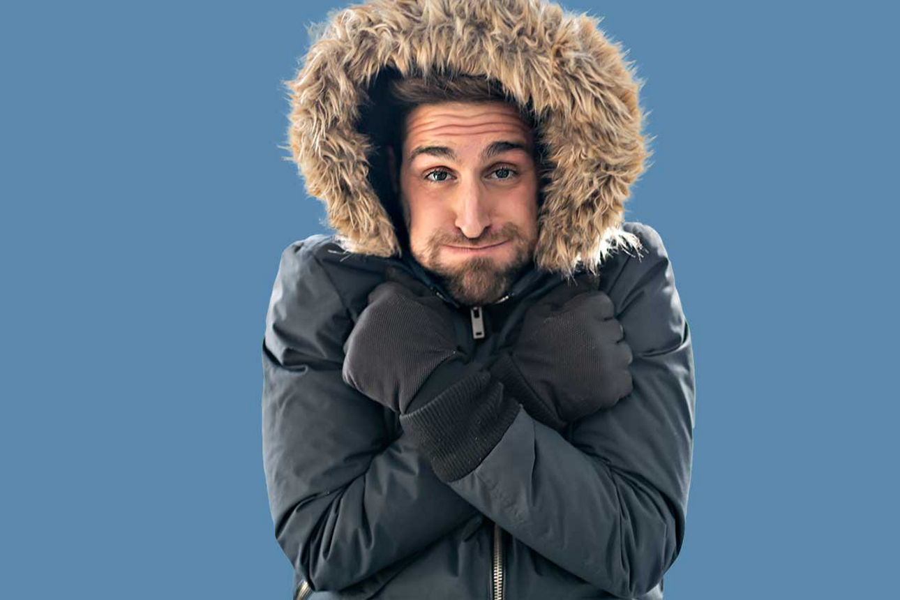 Mann friert in Winterjacke, blauer Hintergrund