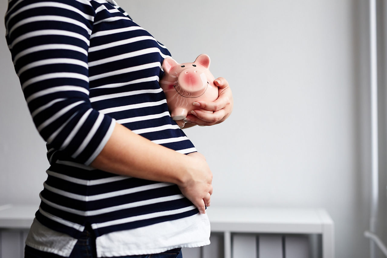 Sparschwein wird von einer schwangeren Frau in gestreiften T-shirt gehalten