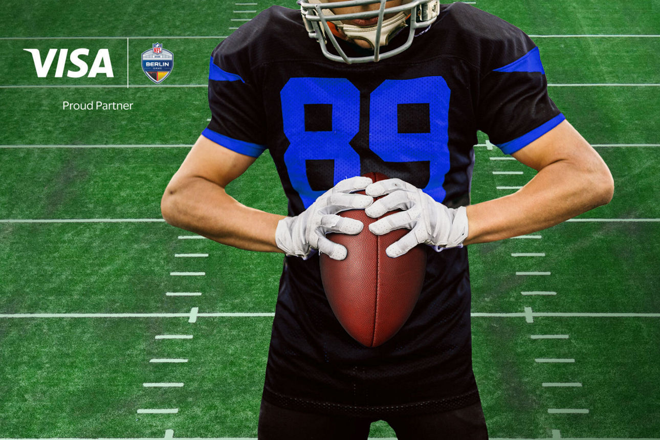 Footballer hält einen Football in der Hand vor einem grünen Hintergrund