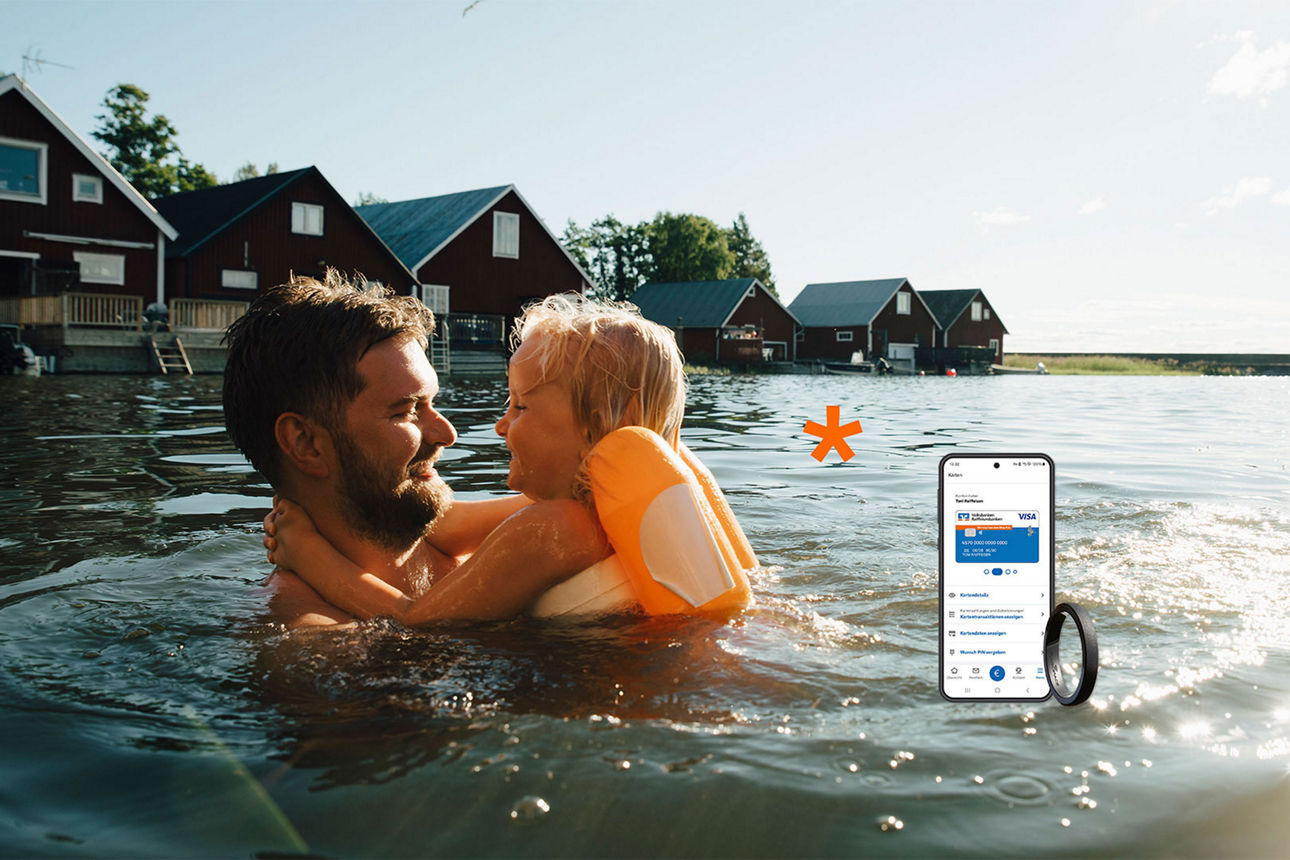 Mann und Kleinkind schwimmen im Badesee, zu sehen ist ein Handy mit digitaler Visa Karte
