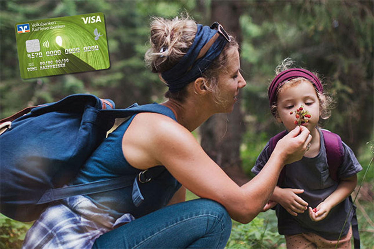 Frau mit Rucksack zeigt ihrem kleinen Kind ein Blatt im Wald