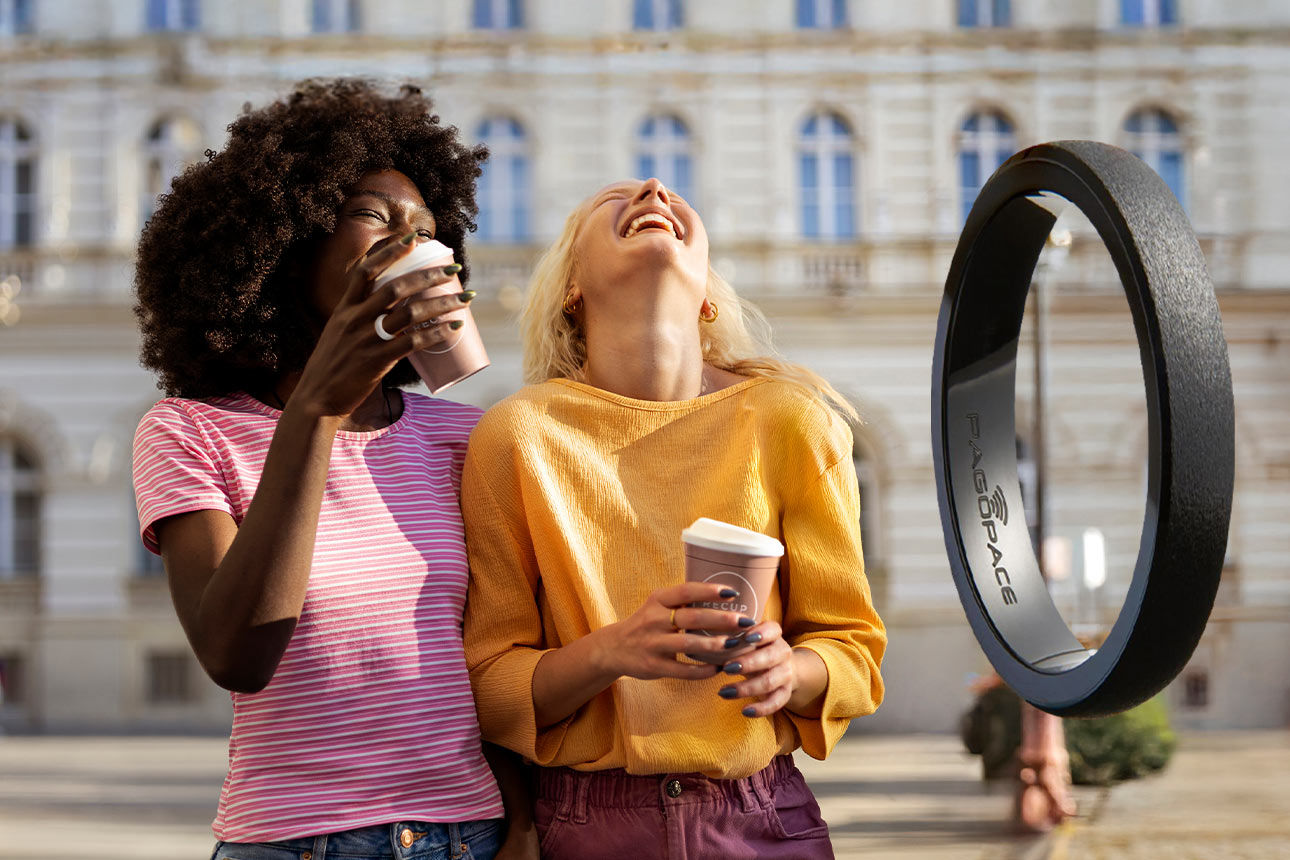 Zwei Frau stehen auf der Straße und halten einen TOGO-Becher in der Hand