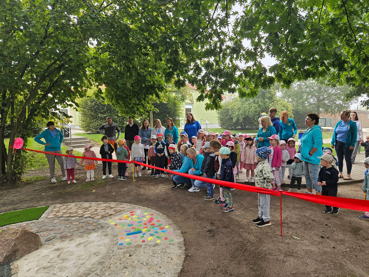 Kinder und Erwachsene stehen hinter Absperrband zum Barfußpfad