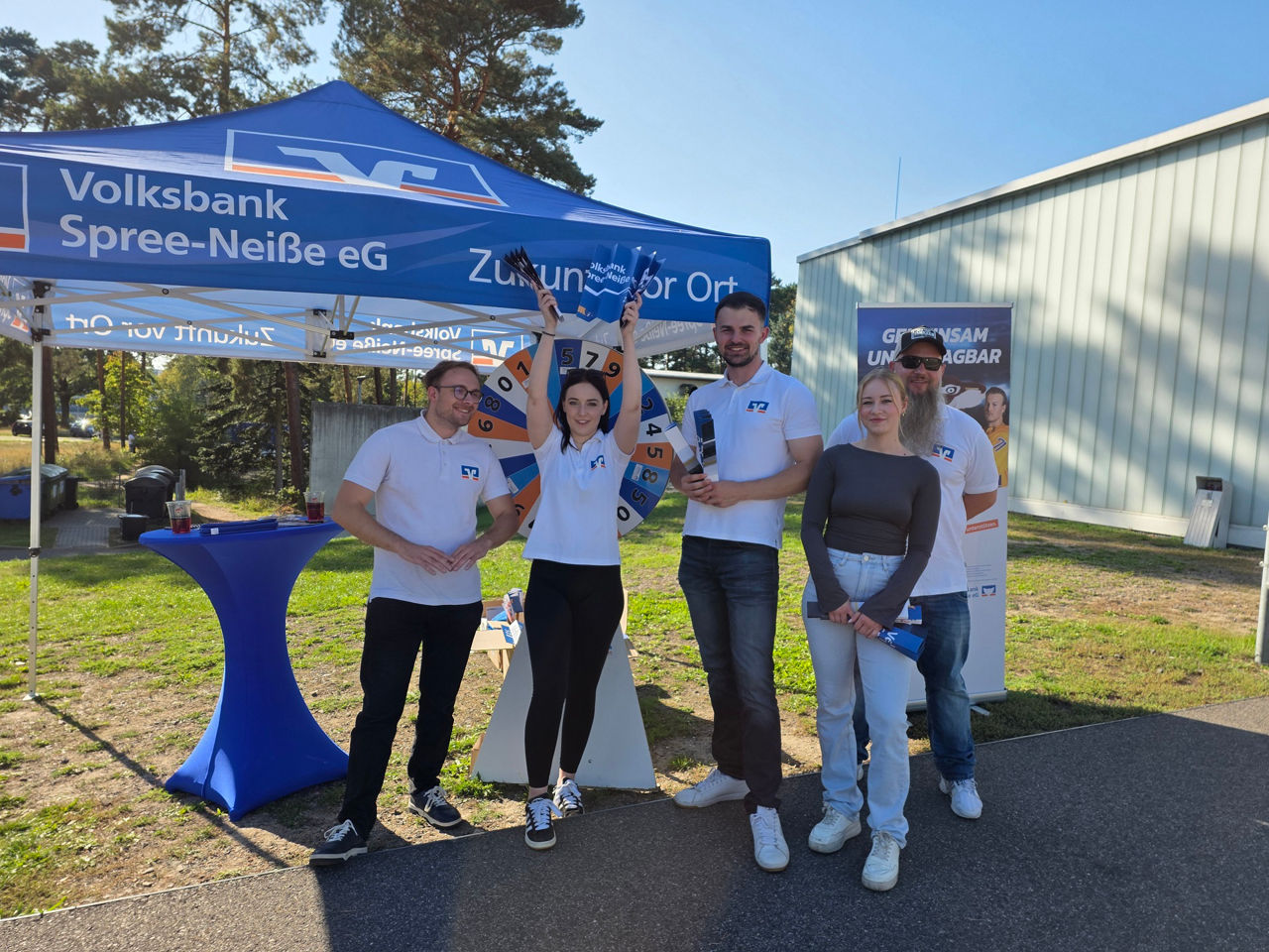 Mitarbeiter der Bank stehen vor einem Zelt