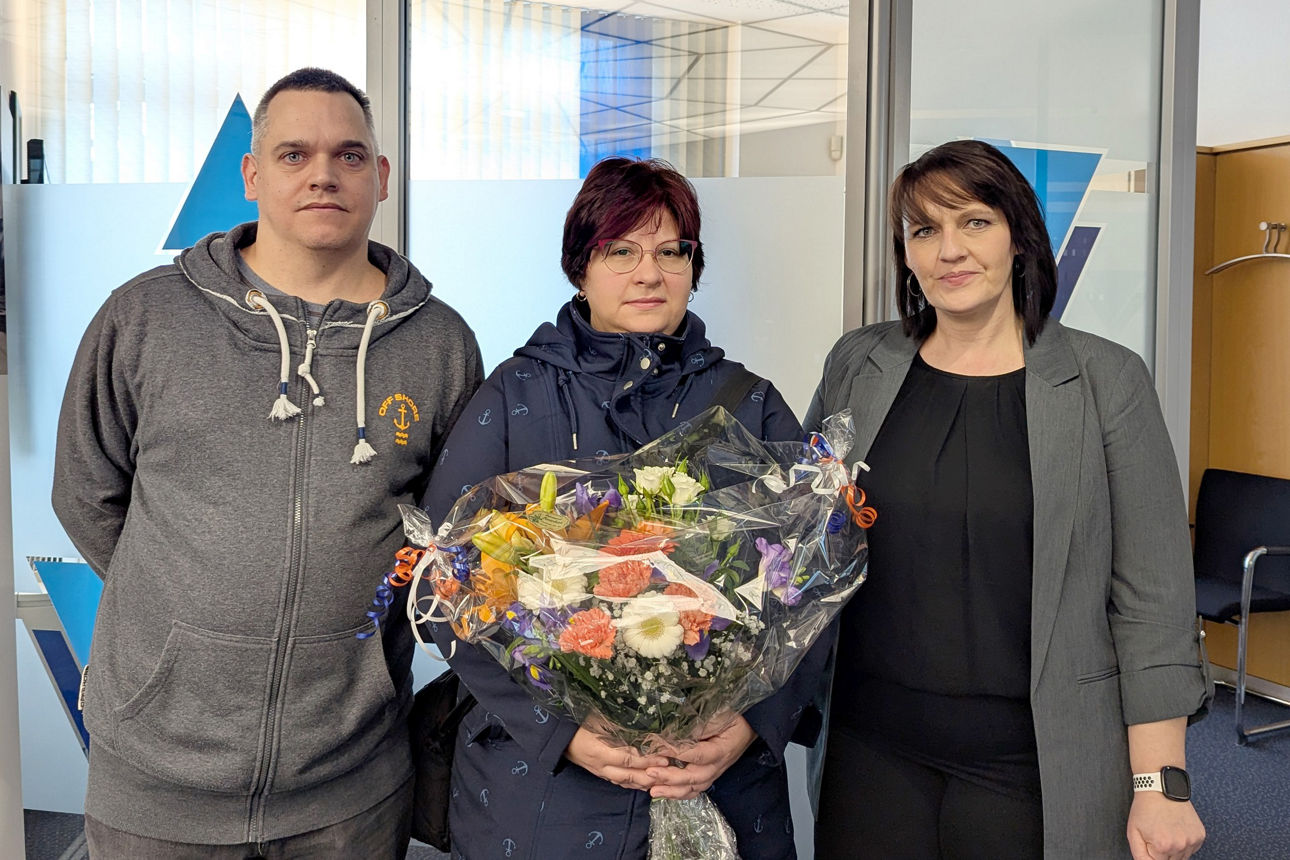 Beraterin übergibt Blumenstrauß an Gewinner-Ehepaar